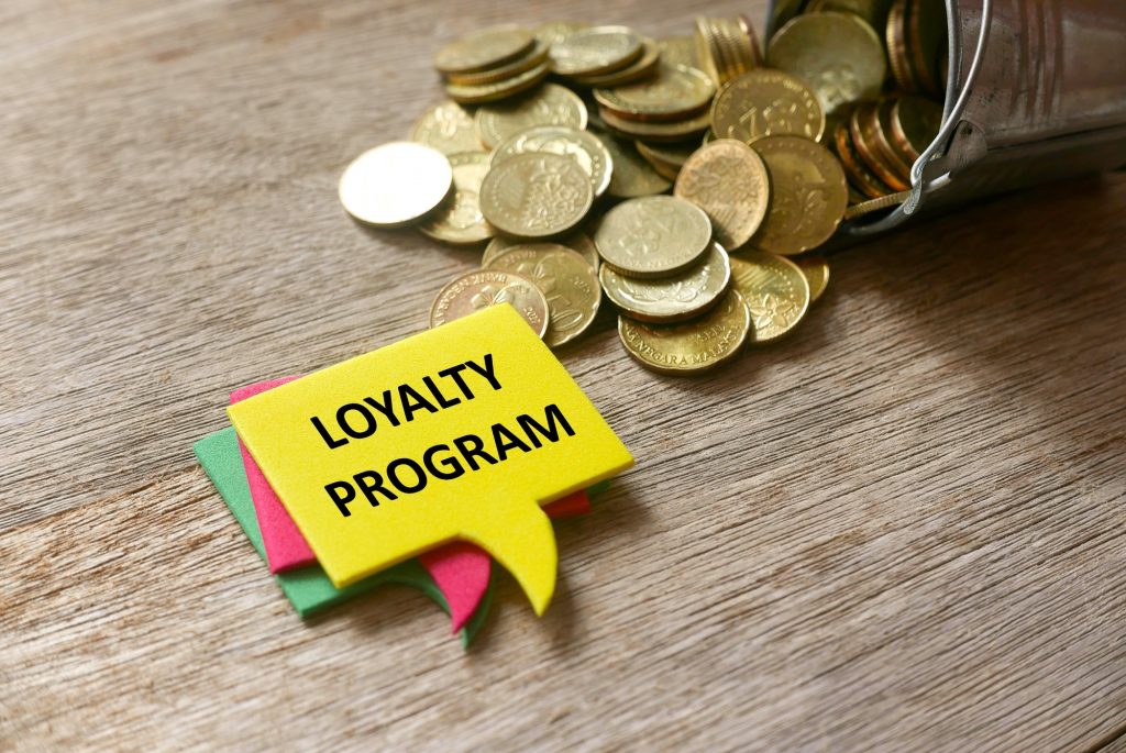 woman purchasing Gold coins and a stack of speech bubbles written with Loyalty Program on wooden background.