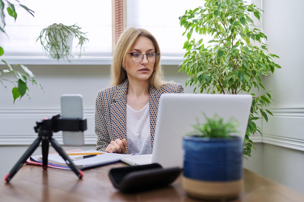 Business woman working at home online using laptop and smartphone.